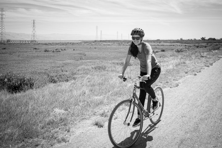 Eve Stoller riding a bike on a Peninsula marsh trail, black and white